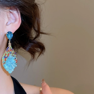 Detailed close-up of bohemian drop earrings with blue crystals and multi-color rhinestones