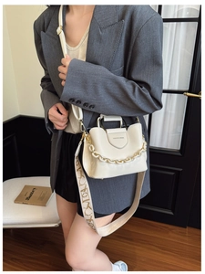 Detail of cream leather bucket bag with decorative chain and floral woven strap