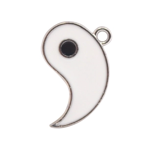 Macro detail of white Tai Chi Yin Yang pendant with metal edge and hanging ring