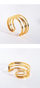 Detail of golden multilayer streamline open bangle with four parallel metallic lines