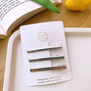 Three silver Y2K hollow metal hair clips on white card with tulip and book background