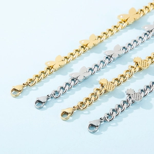 Detail view of butterfly and pineapple charms on gold and silver stainless steel bracelets