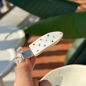 Detail of colorful rhinestones on a white acetate duckbill hair clip for styling