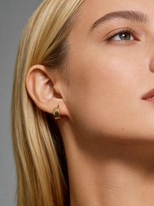 Close-up of elegant wide gold plated S925 sterling silver hoop earring worn by a model