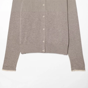 Taupe knit cardigan with round neck and elegant lace sleeve detailing on plain background