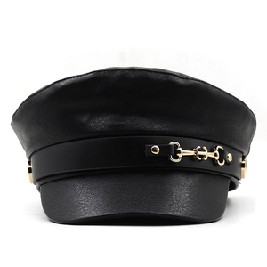 Detail of black faux leather baker boy hat featuring a gold metal horsebit buckle strap