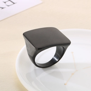 Detail of square black titanium ring with a brushed matte finish on a ceramic plate