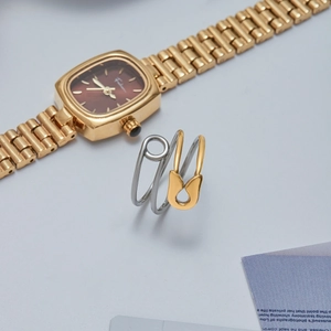 Detailed close-up of a creative gold and silver safety pin ring on a grey surface