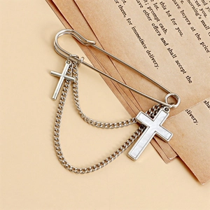 Silver safety pin brooch with white shell cross pendants and chains on vintage paper