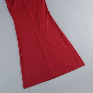 Detailed close-up of red knit dress showing fine stitching and side pleat craftsmanship