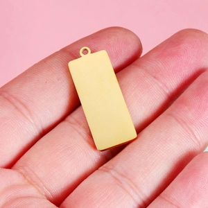 Polished gold rectangular stainless steel pendant held on palm with smooth mirror finish
