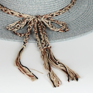 Detailed macro view of light blue woven straw hat featuring a tricolor bow and fringe