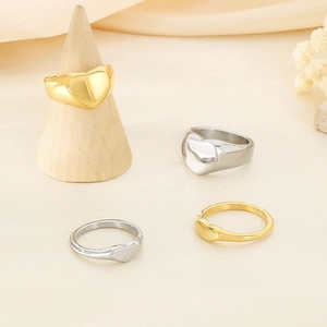 Polished gold and silver heart rings on a minimalist wooden cone display stand