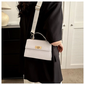 Detail of white crocodile texture bag with gold rotary lock and wide fabric shoulder strap