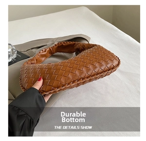 Detail view of woven leather texture and bottom craftsmanship on the brown hobo bag