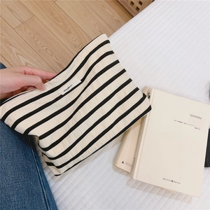 Close-up of a striped cotton makeup bag featuring a Simple Wish woven label