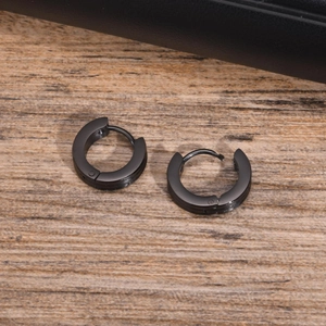 Close-up of black matte stainless steel hoop earrings on a rustic wood background