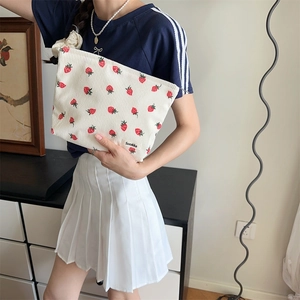 Gros plan d'une pochette en velours côtelé à motif fraise tenue par un mannequin