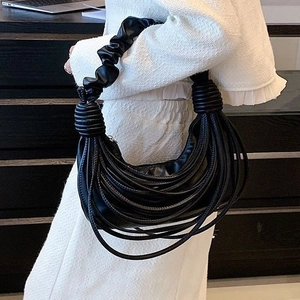 Black crescent shoulder bag with layered fringe and ruched handle on white outfit