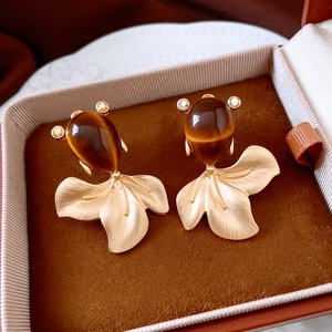 Macro detail of gold goldfish earrings with amber cat-eye stones in a brown jewelry box