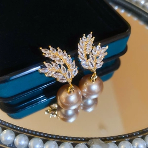 Detail of wheat ear earrings with zircon inlay and golden pearl on a velvet tray
