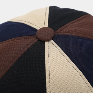 Macro detail of color-block beret showing neat stitching and premium texture on top button