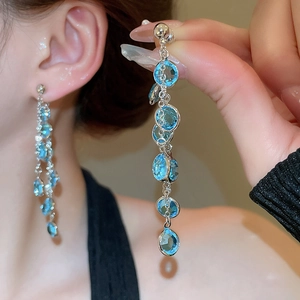 Dettaglio di orecchini lunghi con nappe blu placcati in oro 18 carati e perni in argento