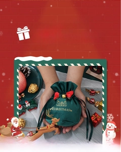 Detail of dark green velvet Christmas drawstring gift bag with gold bell and red bow