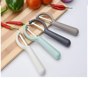 Close-up of four colorful ergonomic vegetable peelers on a wooden cutting board