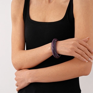 Detail of vintage style wide acrylic bangle with purple floral patterns on model's wrist