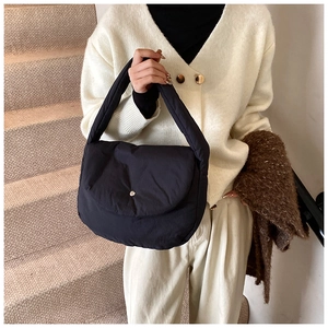 Close-up of a black puffer shoulder bag featuring quilted fabric and a padded strap