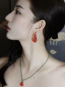 Close-up of elegant gold hollow gourd earrings and green beaded necklace on model