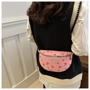 Detail of pink nylon crossbody bag with cherry print and adjustable strap on a model