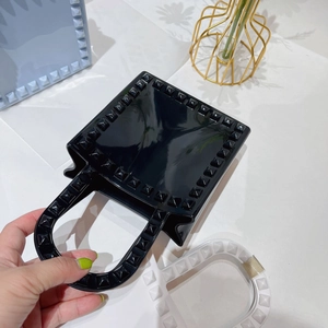 Top-down view of a black PVC mini square bag featuring decorative metal rivets