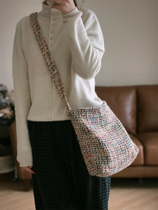 Detail of colorful woven shoulder bag with wide textured strap on a model indoors