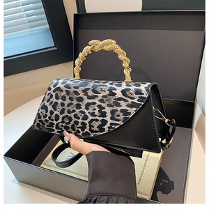 Detailed view of fashionable leopard print bag featuring a unique twisted gold metal handle