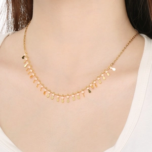 Detail of gold clavicle chain featuring oval drop pendants and beads on a model
