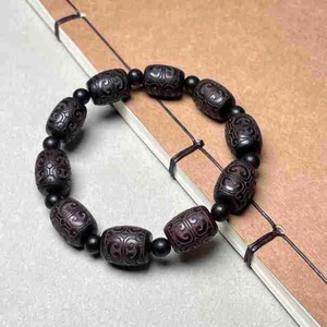 Carved ebony prayer beads with cloud patterns displayed on a vintage book