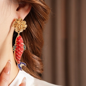 Detail of vintage gold flower earring with a red koi fish pendant worn by a model