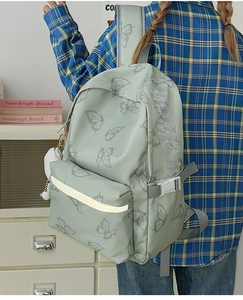 Detail of mint green backpack with butterfly print, reflective strip and plush charm