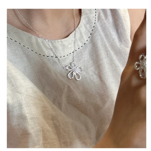 Detail of silver S925 floral necklace and ring set worn by model in natural light