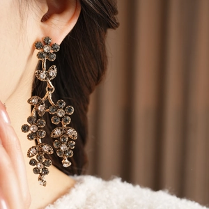 Vintage floral drop earrings with crystals and gold finish on a female model