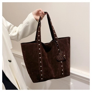Close-up of brown suede tote bag featuring silver studs and a heart shaped charm