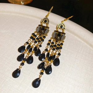 Detail of vintage gold flower earrings with black enamel and teardrop tassel beads