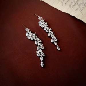 Elegant silver leaf drop earrings with zircon tassels on a dark vintage background