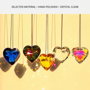 Set of five heart-shaped crystal suncatchers casting rainbow light on a warm wall