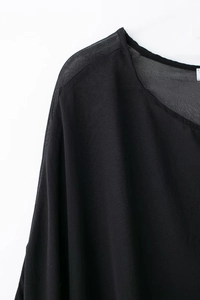 Détail de l'encolure ronde et de l'épaule en mousseline drapée sur cette robe noire