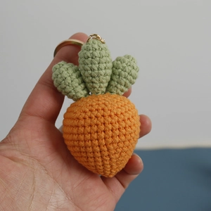 Handmade crochet carrot keychain with orange yarn texture and green leaves
