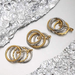 Macro view of layered gold and silver mixed metal brooches with textured ring designs