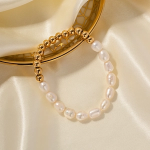 Detail of baroque pearls and 18k gold beads on silk fabric with decorative plate